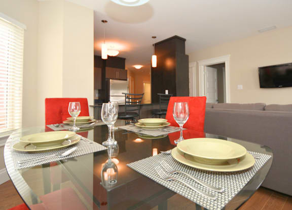 A modern dining room with a glass table set for two.