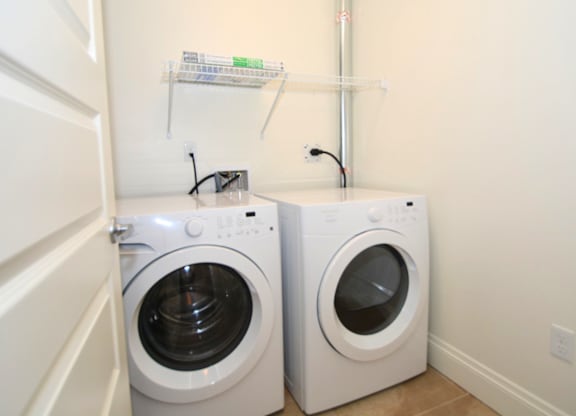 Two white front load washing machines in a small laundry room.