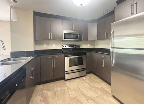 A kitchen with a stove, oven, refrigerator, and microwave.