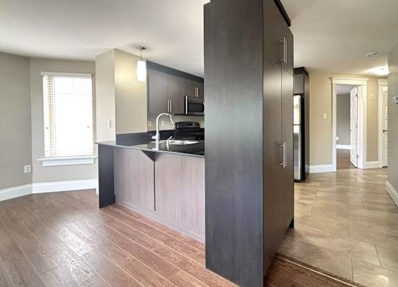 A kitchen with dark wood cabinets and a black countertop.