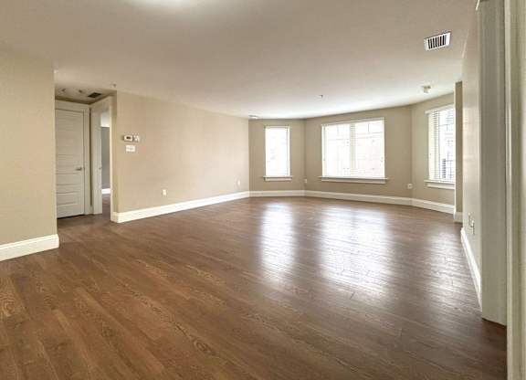 A large empty room with wooden floors and white walls.