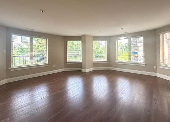 A room with wooden floors and three windows.