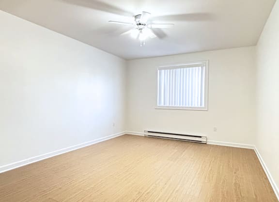 A room with a ceiling fan and a window with blinds.