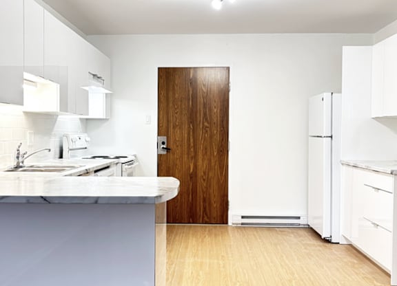 A kitchen with a sink, refrigerator, and cabinets.