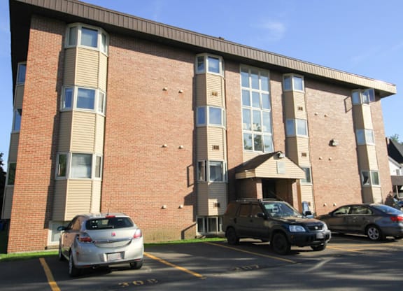 A car is parked in front of a brick building.