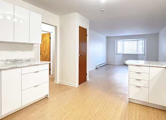 A kitchen with white cabinets and a wooden door.