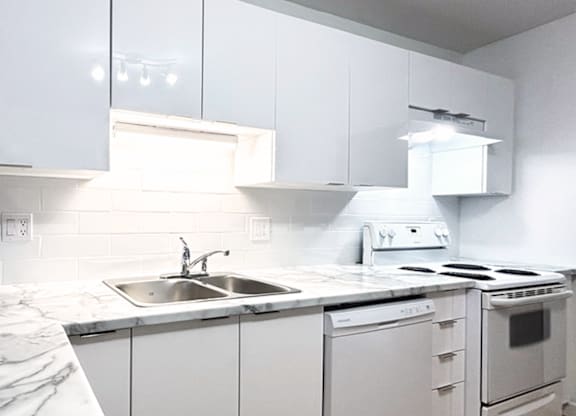 A white kitchen with a sink and stove.