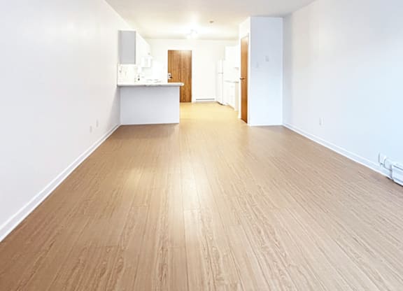 A spacious room with wooden flooring and white walls.