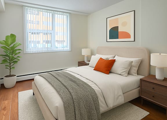 A bedroom with a large bed, a potted plant, and a painting on the wall.