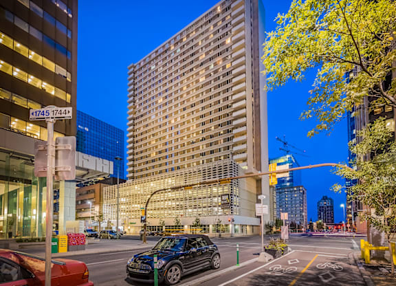 A city street at dusk with cars and tall buildings.