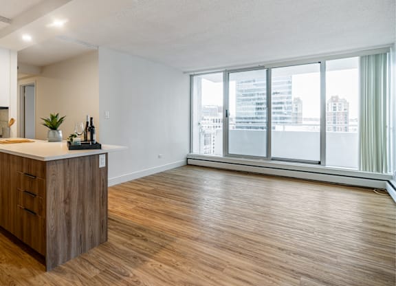 A spacious room with wooden flooring and a large window overlooking a cityscape.