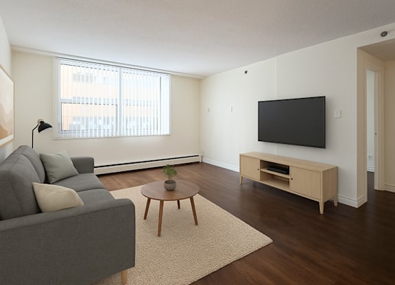 A living room with a grey couch, a wooden coffee table, and a flat screen TV mounted on the wall.