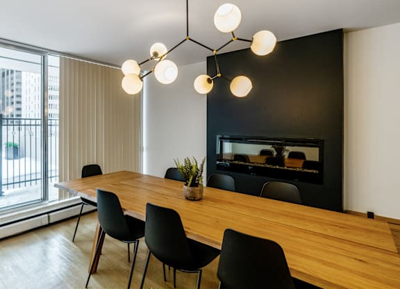 A modern dining room with a wooden table and black chairs.