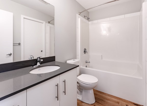 A white toilet sits in a bathroom with a sink and mirror.