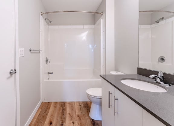 A white bathroom with a wooden floor and a white toilet.