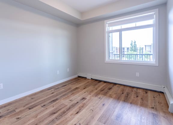 A room with a window and wooden flooring.