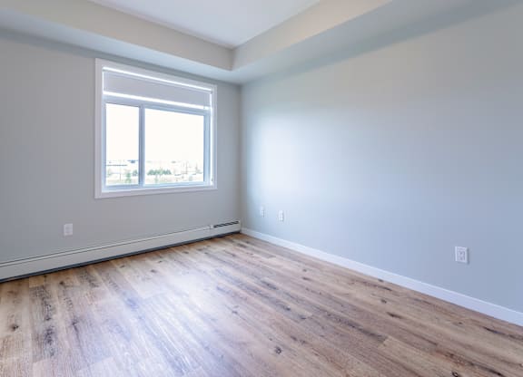 A room with a window and wooden flooring.