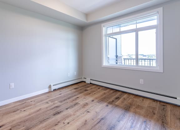 A room with a large window and wooden flooring.