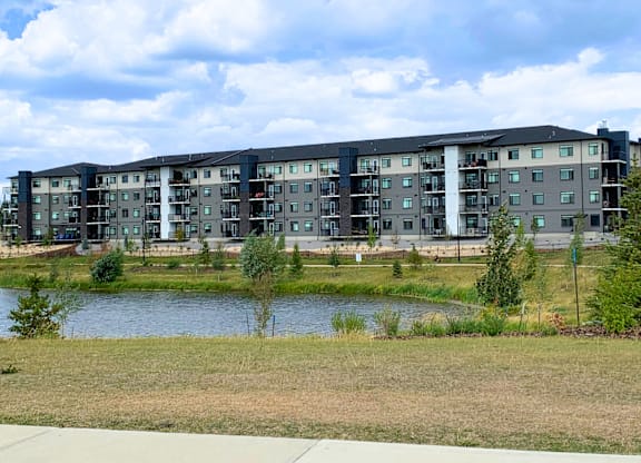 A modern apartment complex with a lake in front.