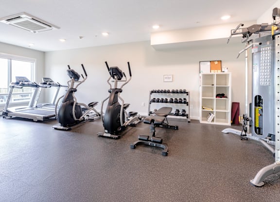 A spacious gym with a variety of equipment including treadmills, stationary bikes, and weight machines.
