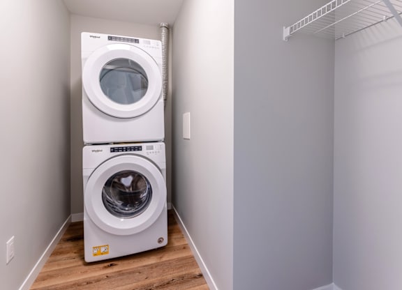 A white dryer and washer are stacked on top of each other in a small laundry room.