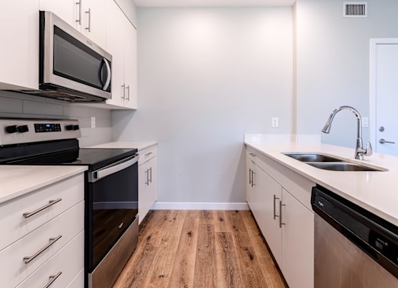 A kitchen with white cabinets and black appliances.