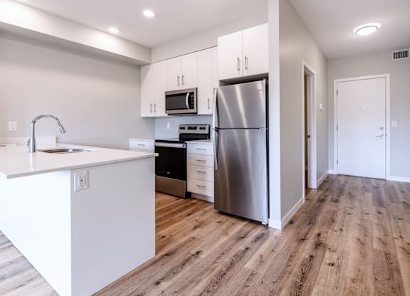 A modern kitchen with a refrigerator, oven, and microwave.