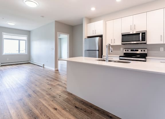 A kitchen with a refrigerator, microwave, and oven.