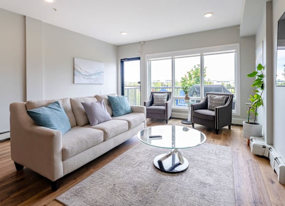 A living room with a grey sofa and a glass table.