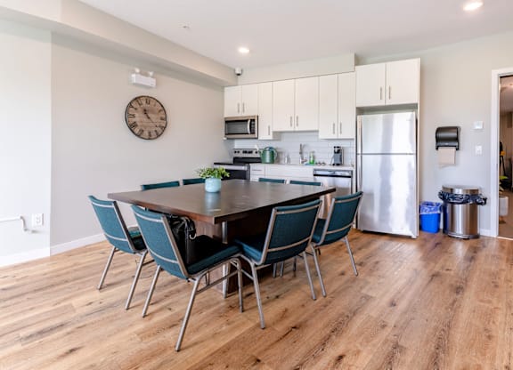 A kitchen with a table and chairs in the foreground and a refrigerator in the background.