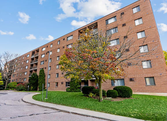 A tall brick apartment building with a tree in front of it.