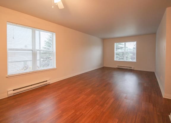 A room with a ceiling fan and wooden flooring.