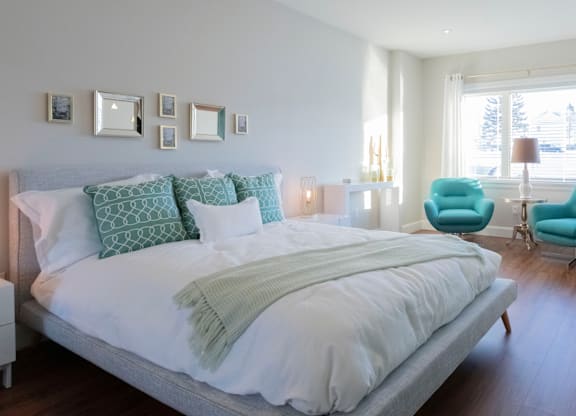A bedroom with a large bed and a blue chair.