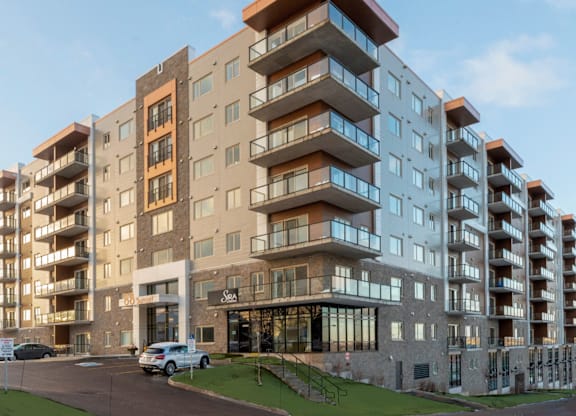 A modern apartment building with cars parked in front.