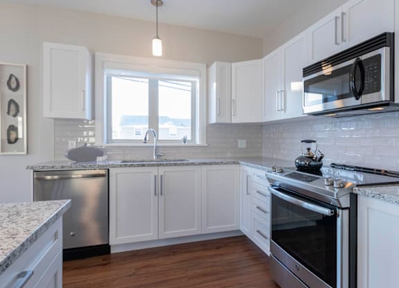 A kitchen with white cabinets and a stainless steel dishwasher.