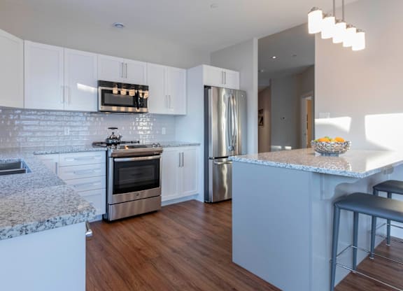 A modern kitchen with white cabinets and a marble countertop.