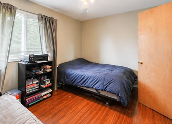 A bedroom with a bed, a ceiling fan, and a bookshelf.