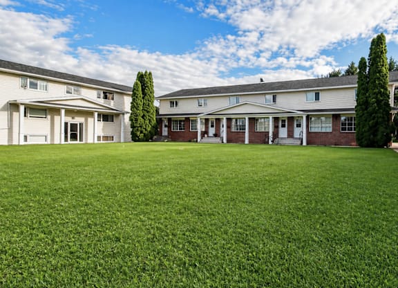 A row of houses with a green lawn in front.