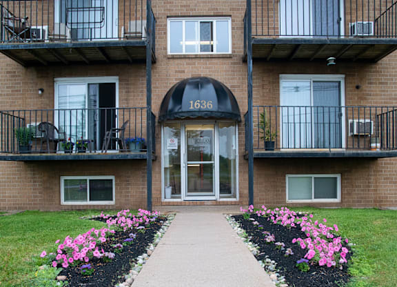 The front of apartment building number 1636 with a walkway and flower beds.