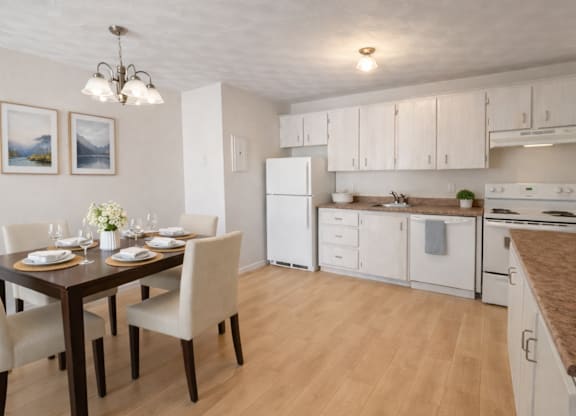 A kitchen with a table set for two and a refrigerator.