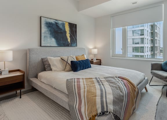 A bedroom with a large bed and a painting on the wall.
