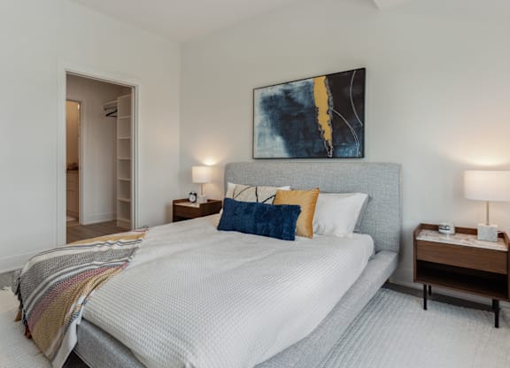 A bedroom with a large bed and a painting on the wall.