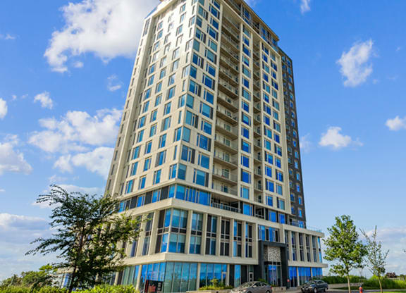 A tall building with many windows and cars parked in front.