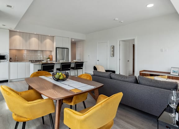 A modern kitchen with a dining table and yellow chairs.