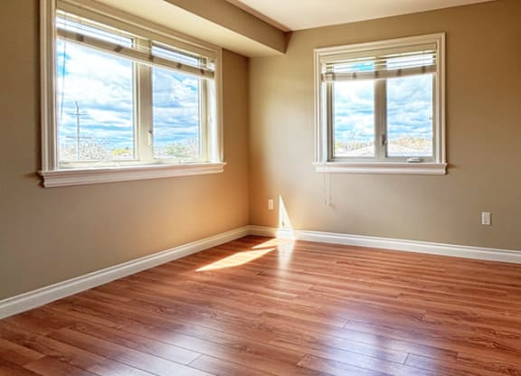 A room with wooden floors and two windows.