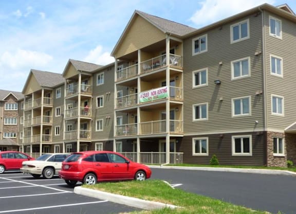 A row of apartment buildings with a red car parked in front.