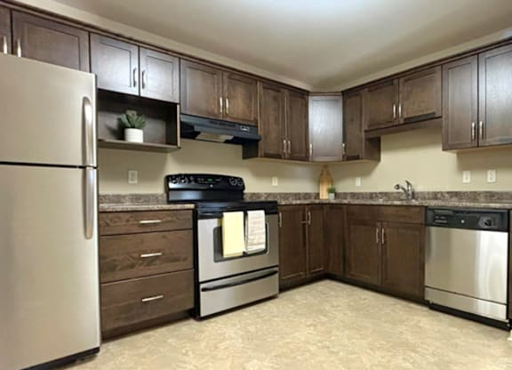 A kitchen with a refrigerator, oven, and sink.