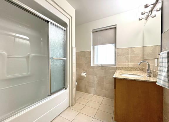 A bathroom with a sink, mirror, and shower.