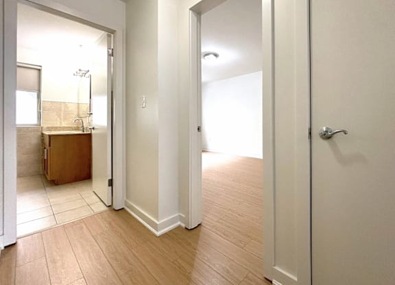 A white door is open to a room with wooden floors.