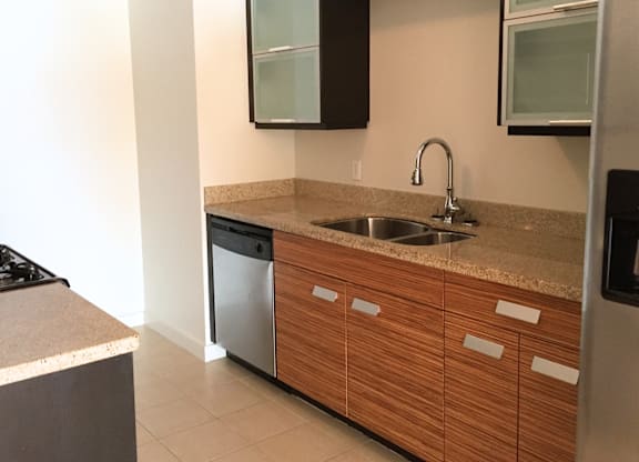 A kitchen with a sink, dishwasher, and refrigerator.